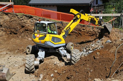 Excavator with wheels on dirt at construction site.