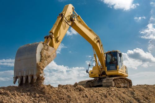 Excavator with claw arm on dirt.